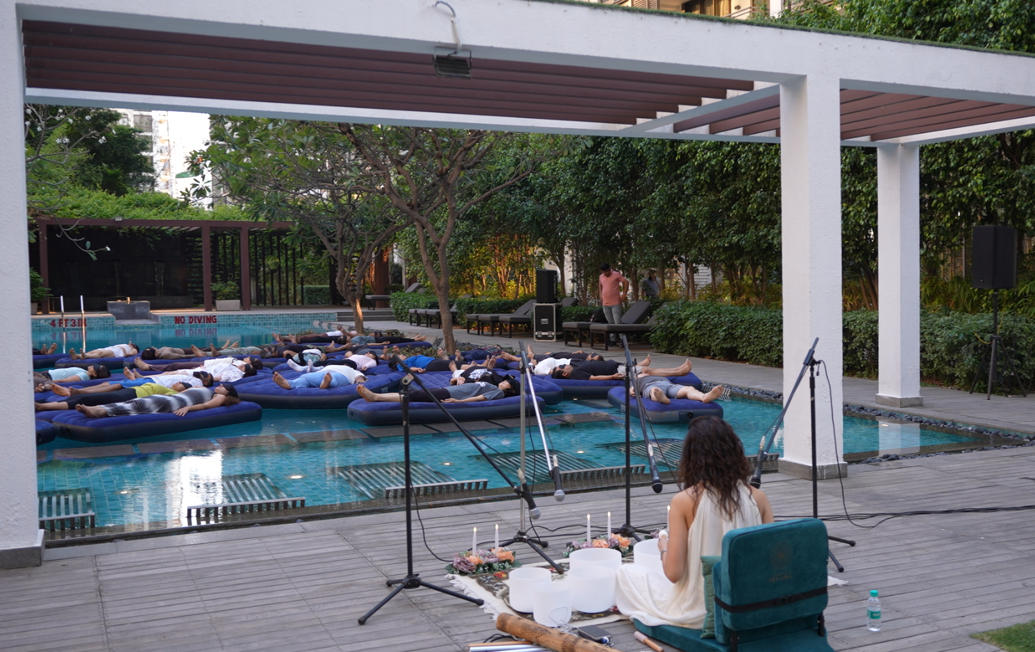 Aqua sound healing session — participants floating on mats in an outdoor pool
